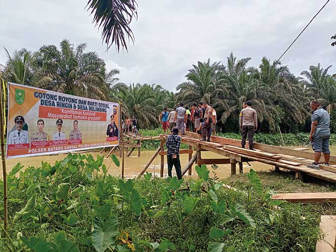 Personel Polsek Batang Gansal bersama warga membangun jembatan penghubung Desa Ringin dan Desa Belimbing, Kamis (19/1/2023).
