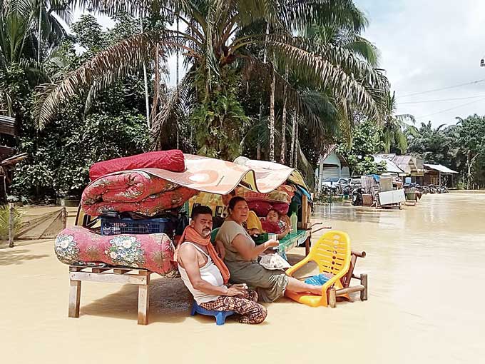 Warga Desa Lubuk Ramo, Kecamatan Kuantan Mudik berusaha menyelamatkan barang-barangnya saat dilanda banjir, Jumat (10/3/2023).