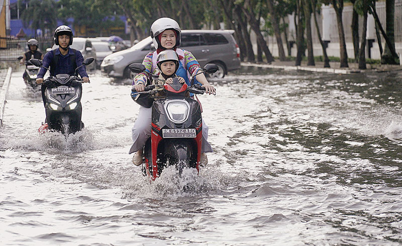 Pengendara sepeda motor menerobos genangan airÂ saat melintas diÂ JalanÂ Cut Nyak Dhien di samping Kantor Gubernur Riau, Kamis (16/11/2023). Hujan sesaat yang mengÂ­guyur Kota Pekanbaru membuat beberapa jalananÂ tergeÂ­nangÂ air hingga menyulitÂ­kan pen