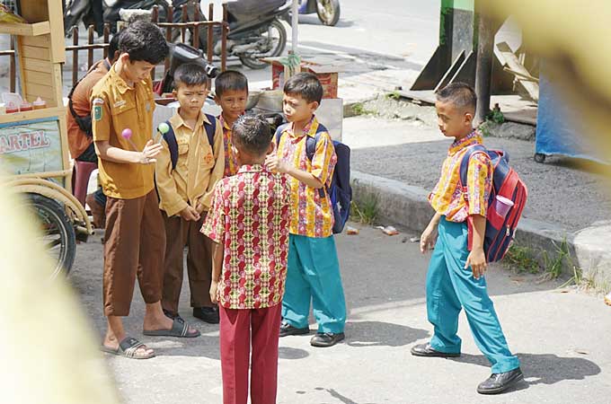 Sejumlah anak-anak berpakaian seragam bermain lato-lato di luar pekarangan sekolah dasar negeri, Jalan HR Soebrantas, Kamis (12/1/2023). Dinas Pendidikan Kota Pekanbaru melarang keras permainan lato-lato di area sekolah karena dinilai bisa mencederai anak
