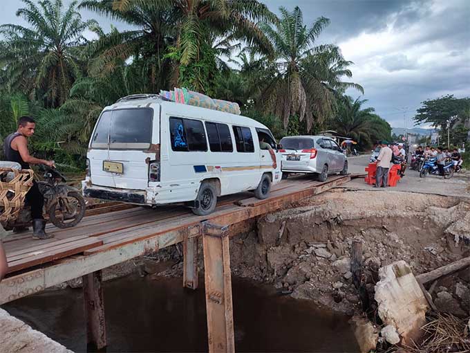 Kendaraan roda dua dan mini bus AKAP terlihat melintasi jembatan sementara yang terbuat dari plat dan rangka besi di titik ruas jalan provinsi Riau-Sumut tepatnya di Dusun V Desa BPTJ, Kecamatan Bangun Purba, Kabupaten Rohul, Â Sabtu (25/3/2023) petang.