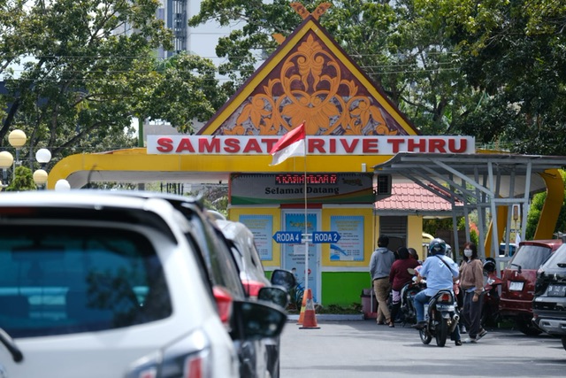 Wajib pajak tampak antusias membayar pajak kendaraan bermotornya melalui layanan Driver Thru yang ada di Samsat Simpang Tiga, Jalan Jenderal Sudirman, Rabu (1/3/2023).