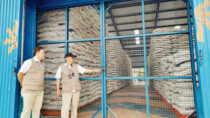 Dua petugas Bulog Dumai memperlihatkan stok beras di gudang Bulog yang berada di Jalan Sultan Syarif Kasim Dumai, Ahad (19/2/2023).