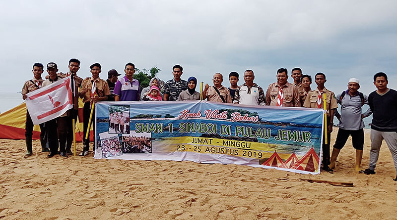 KIBARKAN: Belasan anggota Pramuka asal Gudep SMA Negeri 1 Sinaboi membentangkan spanduk sebagai tanda telah dilaksanakannya kemah bernuasan wisata bahari di Pulau Jemur.(Syahri Ramlan/riau pos)