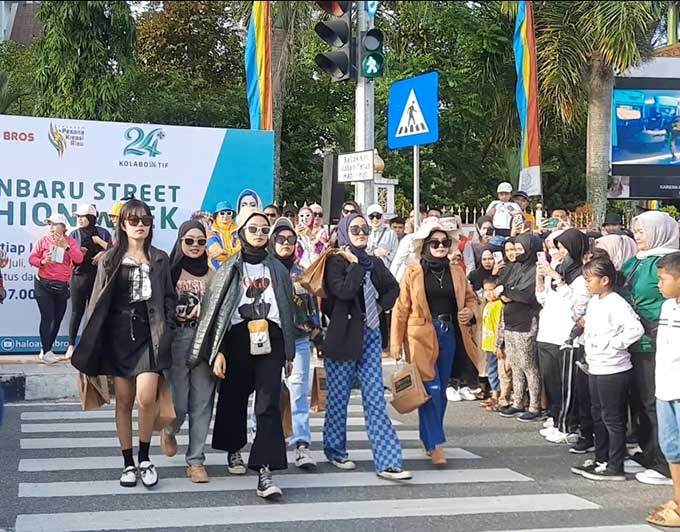 Para model Pekanbaru Street Fashion Week pamerkan pakaian saat berjalan di zebra cross Tugu Zapin, Jalan Gajah Mada Pekanbaru di lokasi Car Free Day, Ahad (31/7/2022).