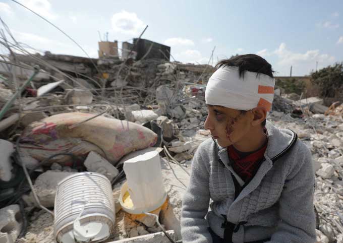 Seorang anak laki-laki Suriah duduk di puing-puing bangunan yang runtuh akibat gempa, Ahad (12/2/2023). Ia kehilangan keluarganya saat gempa mengguncang Kota Jindayris, Aleppo, Suriah.