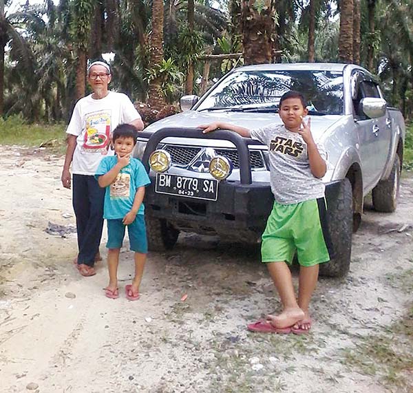 H Muhammad Handoko bersama dua cucunya di lahan perÂ­keÂ­Â­bunan sawit miliknya, beberapa waktu lalu. (Lismar Sumirat/riau pos)