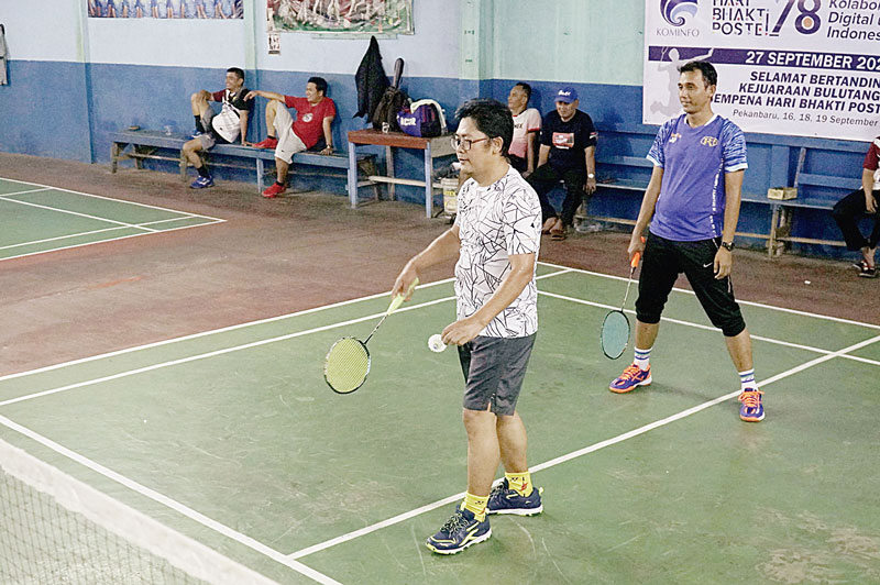 Direktur Utama Riau Pos Ahmad Dardiri berpasangan dengan Zelfiyandi melakukan servis saat mengikuti pertandingan bulutangkis Hari Bakti Pos Telekomunikasi (Postel) ke-78 di GOR Arya Cipta Sport, Jalan Cipta Karya, Kecamatan Tuah Madani, Pekanbaru, Senin (