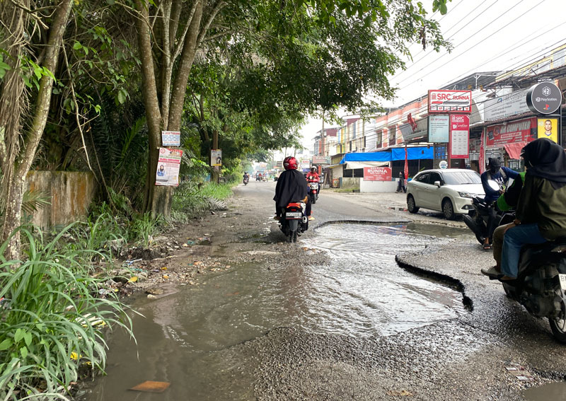 Pengendara sepeda motor melewati lubang yang ada di Jalan Bangau Sakti, Kecamatan Binawidya, akhir pekan lalu.