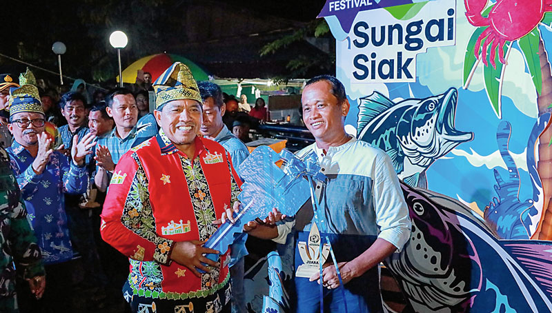 Bupati Siak Alfedri (dua kanan) menyerahkan hadiah secara simbolis kepada pemenang lomba memancing pada malam penutupan FSS 2023 di tepian Sungai Jantan, Siak Sri Indrapura, Ahad (24/12/2023).