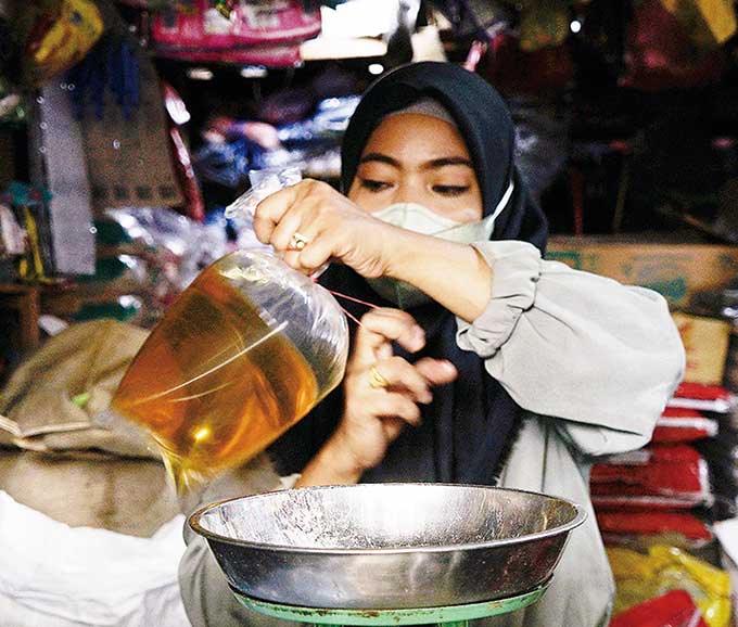 Pedagang menimbang minyak goreng curah yang akan dijualnya dengan harga Rp19 ribu per kilogram di Pasar Limapuluh, Pekanbaru, baru-baru ini.