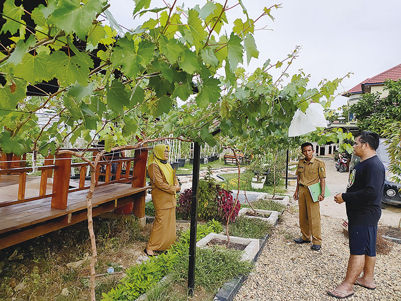 Kepala BPKAD Kuansing, Hendra AP MSi (kanan) berbincang dengan beberapa pegawai terkait proses penanaman bibit anggur di rumah anggur KY di Telukkuantan, belum lama ini.(MARDIAS CAN/RIAUPOS.CO)