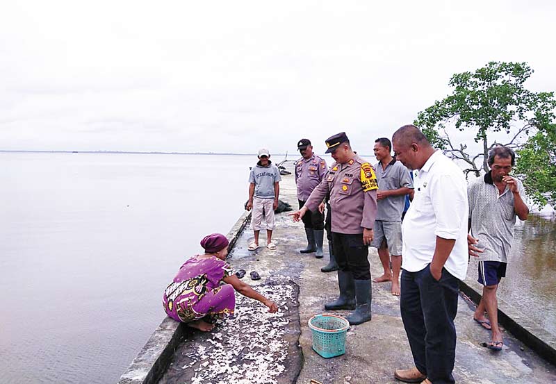 Kapolsek Bengkalis AKP Faisal SH didampingi Kanit Patroli Aiptu Dodik Darmanto, Bhabinkamtibmas Desa Kelapa Pati Laut Aiptu RonalÂ  melihat warga menjemur ikan di Desa Kelapa Pati Laut, Kecamatan Bengkalis, Rabu (27/12/2023).