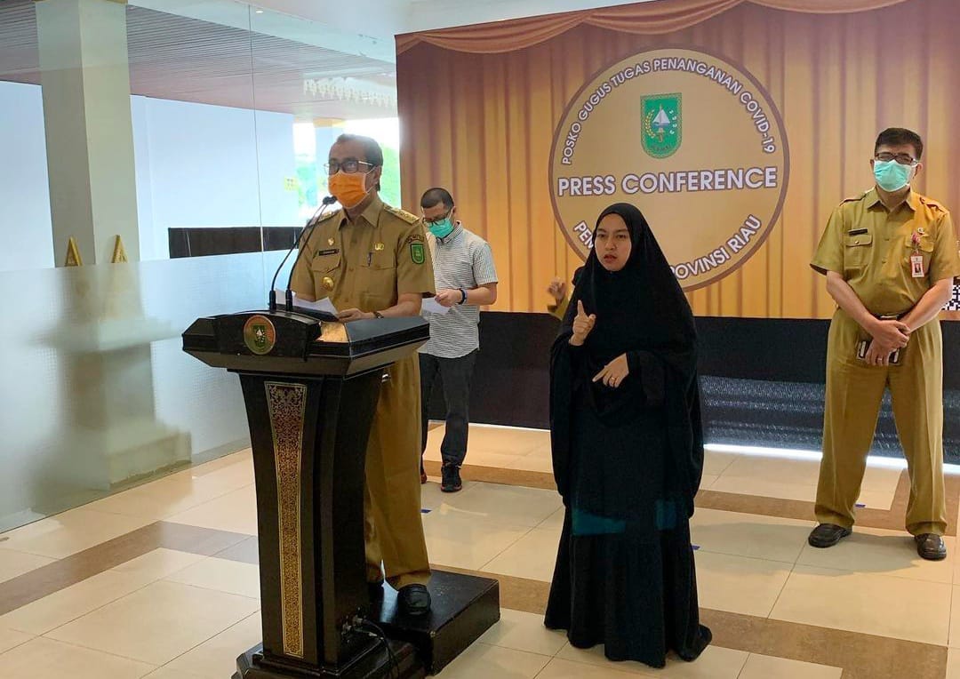 Pendiri Komunitas Tuli Lancang Kuning, Santi Setyaningsih (kanan) saat menjadi juru bahasa isyarat dalam keterangan pers tim Satgas Covid-19 Provinsi Riau beberapa waktu lalu.(IST)