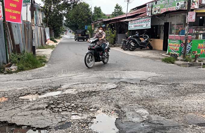 Seorang pengendara melintas di persimpangan Jalan Rajawali dan Jalan Nusa Indah, Kecamatan Sukajadi yang rusak, baru-baru ini.