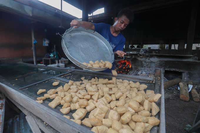 Pekerja memindahkan tahu yang telah digoreng di pabrik pembuatan tahu yang berada di Jalan Payung Sekaki, Kecamatan Payung Sekaki, Rabu (23/2/2022). Harga tahu goreng mengalami kenaikan karena adanya kenaikan harga bahan pokok pembuatan tahu yaitu kedela