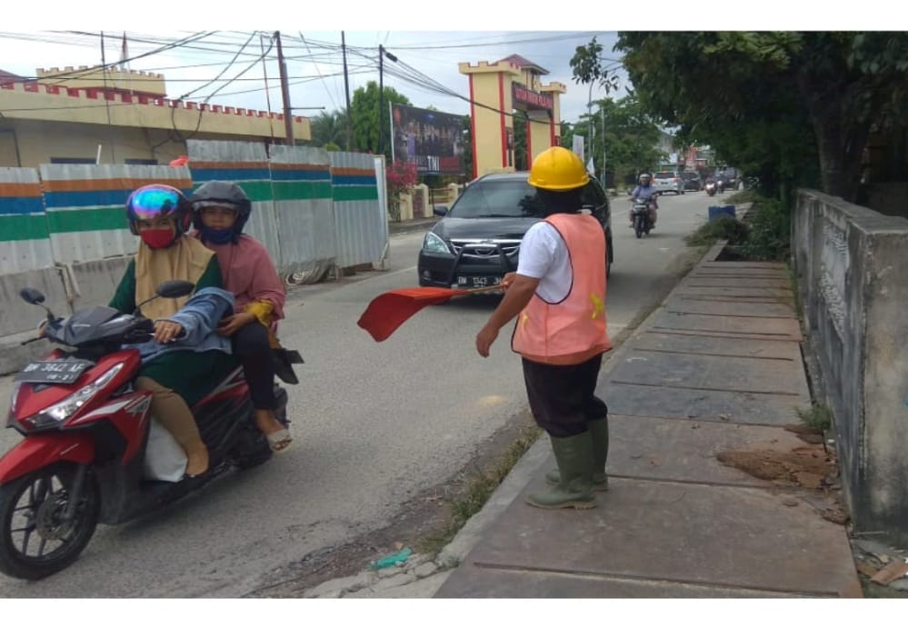 Pekerja tampak mengatur kelancaran lalulintas di sela-sela pengerjaan pembangunan jaringan perpipaan air limbah di wilayah Sukajadi, Kota Pekanbaru belum lama ini.