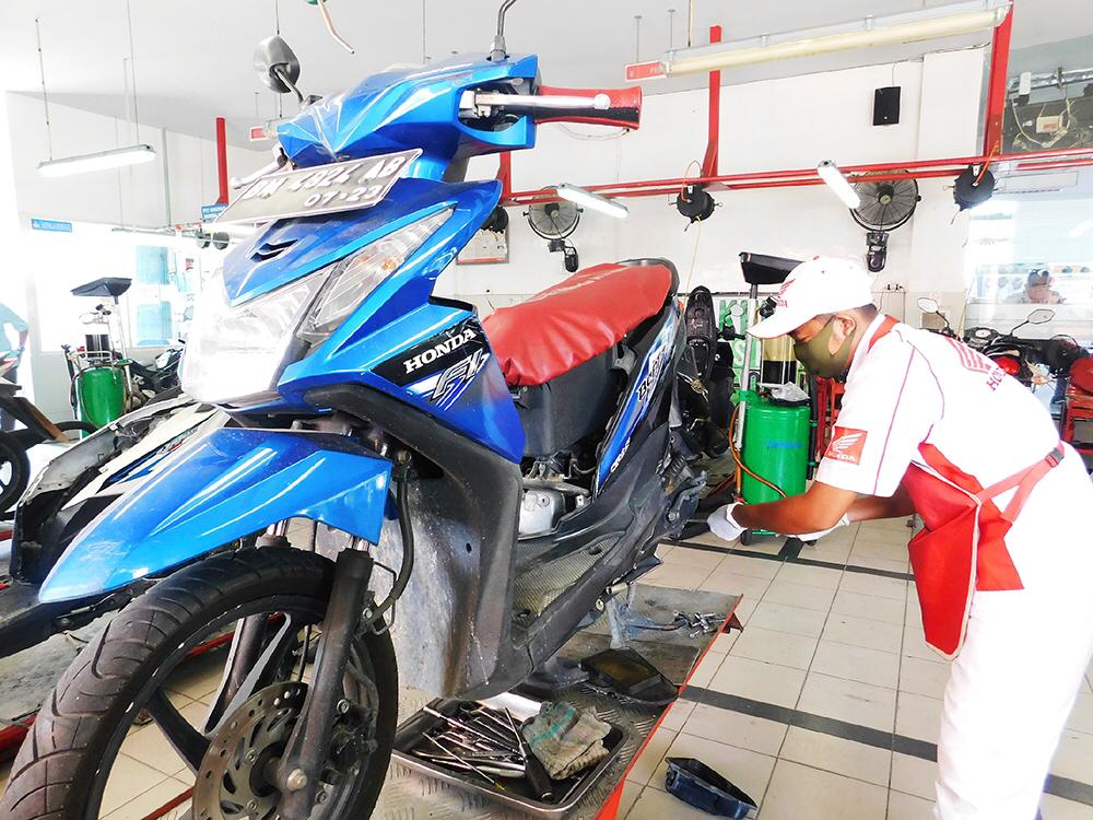 Foto: Salah seorang Mekanik Honda sedang melakukan servis motor Honda milik konsumen dengan menggenakan masker dan sarung tangan.(HONDA FOR RIAUPOS.CO)