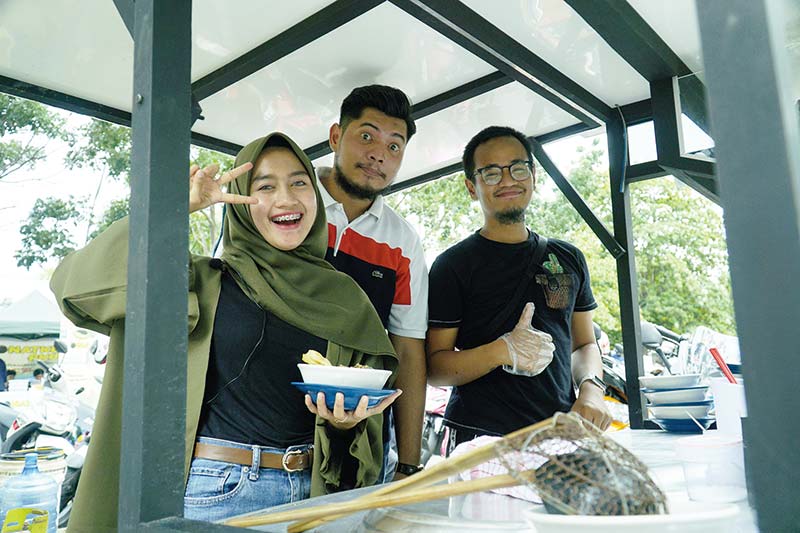 MAKAN MI AYAM: Syahra Regina (kiri), bersama owner Mi Ayam Andalan M Putra Geramezio (tengah) dan Bagus Priyo (kanan) memperlihatkan mi ayam yang berada di Bundaran Kris Jalan Diponegoro, Jumat (6/12/2019). (Ft Bayu Saputra/Riaupos)