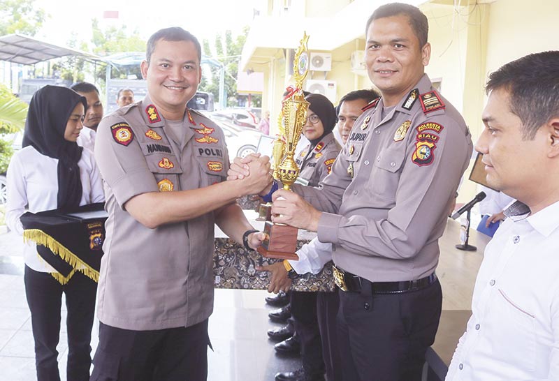 Beri PIALA: Kapolresta Pekanbaru AKBP Nandang Mu&rsquo;min Wijaya (kiri) memberikan piala kepada Kapolsek Tampan AKP Juper Lumban Toruan saat ekspos Operasi Antinarkoba 2019 di Mapolresta Pekanbaru, Senin (9/12/2019). Polsek Tampan berhasil mengungkap kas