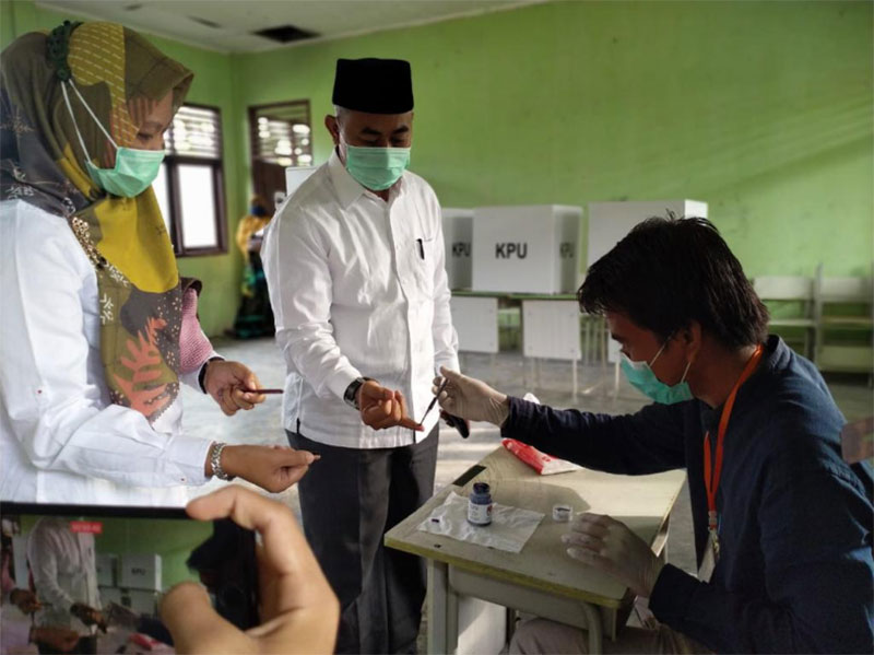 Sujarwo dan istri memperlihatkan jari bertinta sebagai tanda telah melaksanakan hak pilihnya di TPS 1 Benhil, Mempura, Rabu (9/12/2020).(MONANG LUBIS/RIAUPOS.CO)