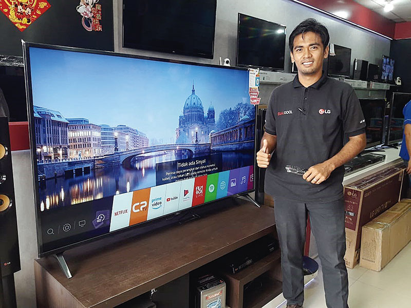 Sales Marketing Batam Elektronik Pekanbaru Alpen mengacungkan jempol saat mempromosikan televisi, Rabu (15/1/2020). (BATAM ELEKTRONIK FOR RIAU POS)