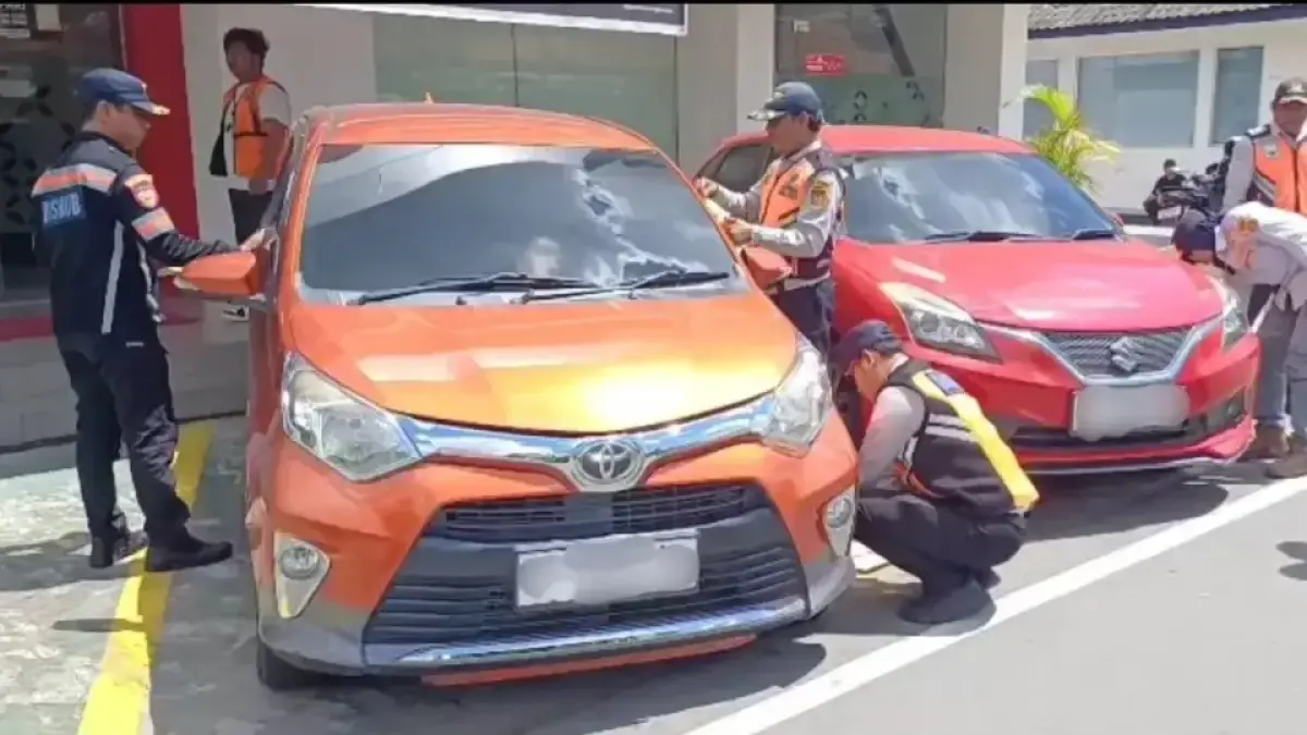 Petugas Dishub menindak kendaraan yang parkir di depan Plaza Telkom Samarinda dengan menggembosi ban dan memasang stiker peringatan. 